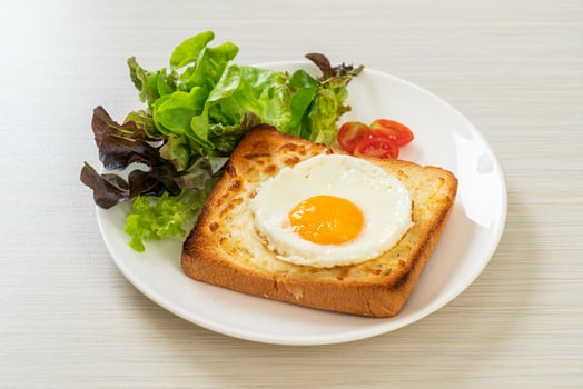 Homemade bread toasted with cheese and fried egg on top with vegetable salad for breakfast photo