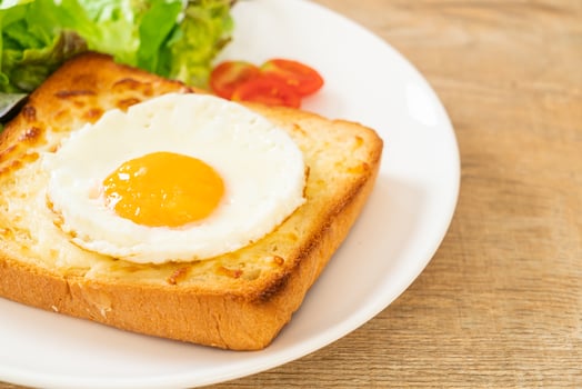 Homemade bread toasted with cheese and fried egg on top with vegetable salad for breakfast photo