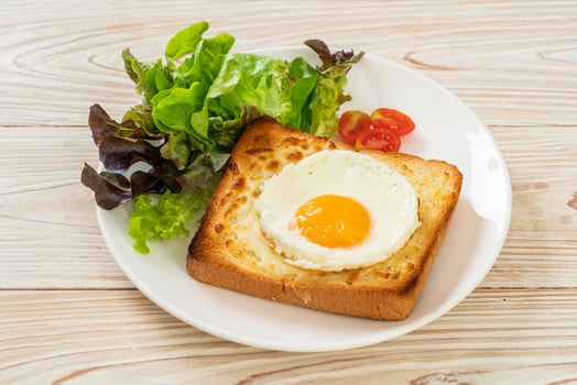 Homemade bread toasted with cheese and fried egg on top with vegetable salad for breakfast photo