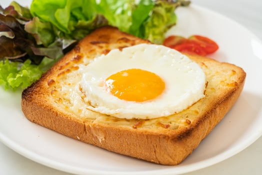 Homemade bread toasted with cheese and fried egg on top with vegetable salad for breakfast photo