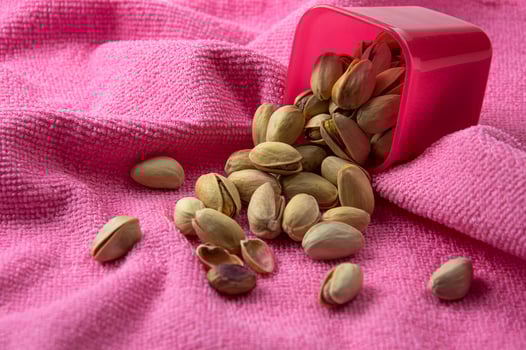 Pistachios in container on pink background photo