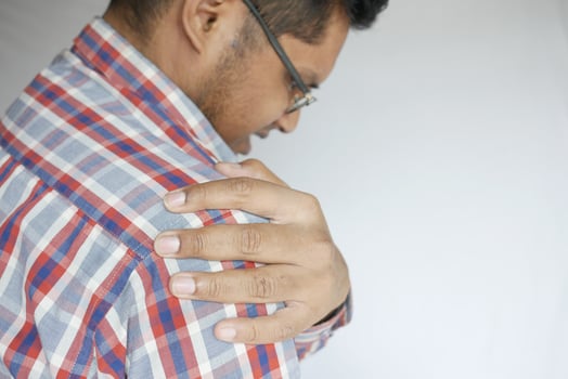 man suffering pain in hand looking down photo