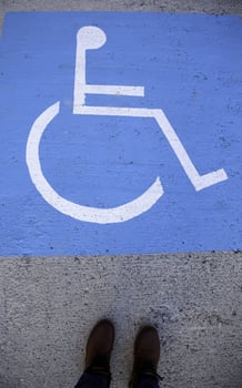 Feet on a handicapped sign on the asphalt photo