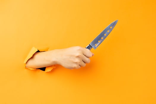 Hand holding knife protruding from the background photo