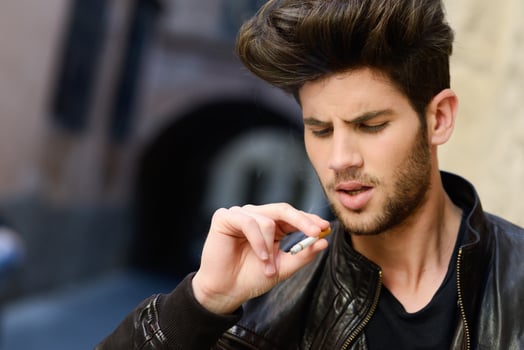 Young man smoking a cigarette in urban background photo