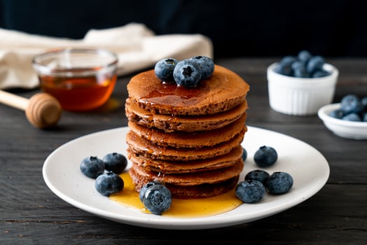 Chocolate pancake stack with blueberry and honey on a plate photo