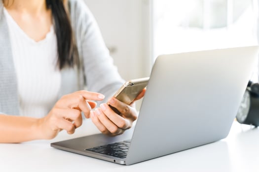 young woman using mobile phone with laptop computer. photo
