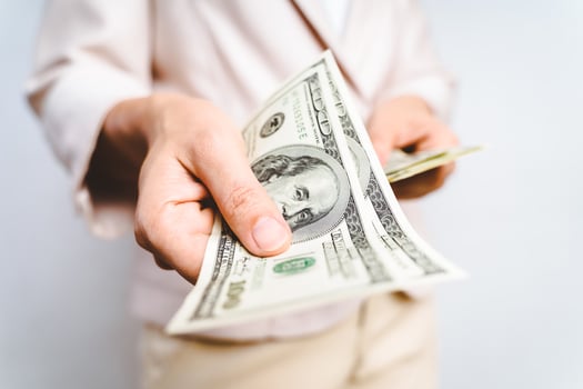 Closeup of business woman hands proposing money us dollar bills on white background. Money Concept. photo