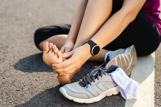 Running injury leg accident- sport woman runner hurting holding painful sprained ankle in pain. Female athlete with joint or muscle soreness and problem feeling ache in her lower body. photo