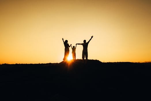 silhouettes of a happy young happy family against an orange sunset photo