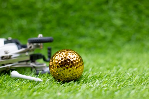 Golden golf ball is on green grass photo