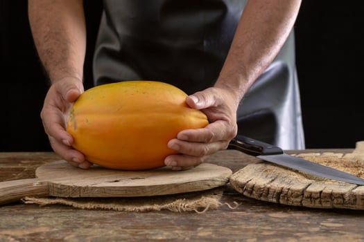 Ripe papaya fruit in the hands of men on wooden background photo