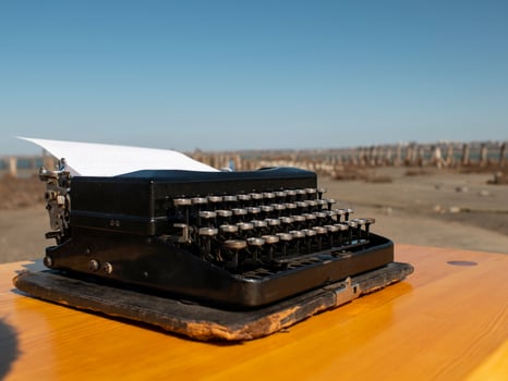vintage typewriter on a wooden table, handmade on a blue sky background photo