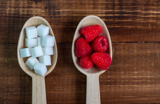 Healthy raspberries and uhealthy sugar in wooden spoons photo