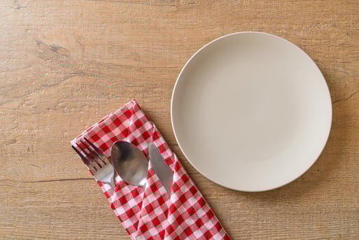 Empty plate or dish with knife, fork, and spoon on wood tile background photo