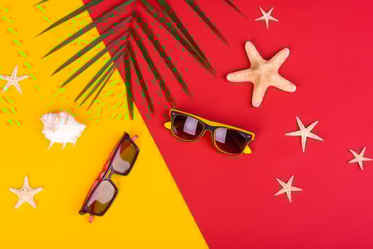 Glasses and hat with shells and sea stars on a colored background photo