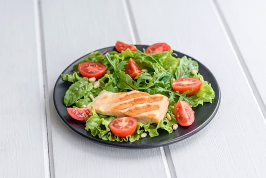 Delicious fresh salad with fish, tomatoes and lettuce leaves photo