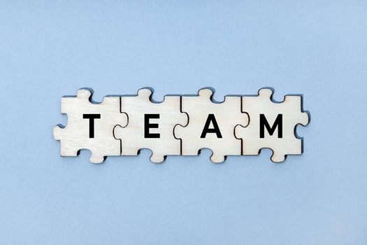 Team word on wooden puzzle pieces isolated on blue background. Top view photo
