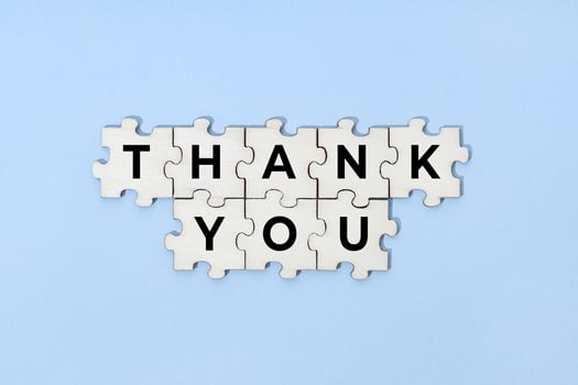 Thank you phrase on wooden puzzle isolated on blue background. Top view photo