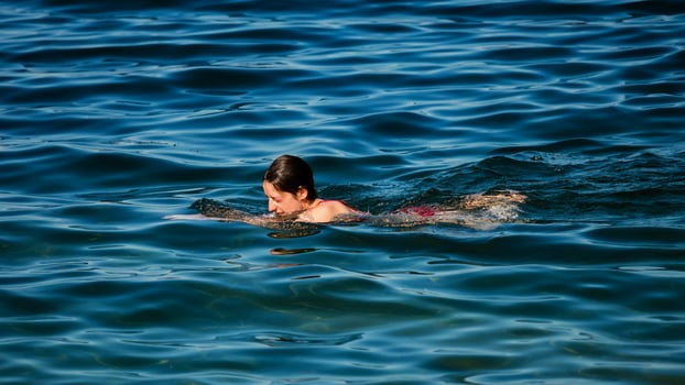 A young girl swims in the crystal clear water of a mountain lake. photo