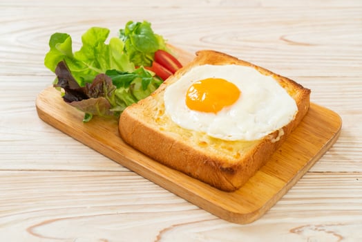 Homemade bread toasted with cheese and fried egg on top with vegetable salad for breakfast photo