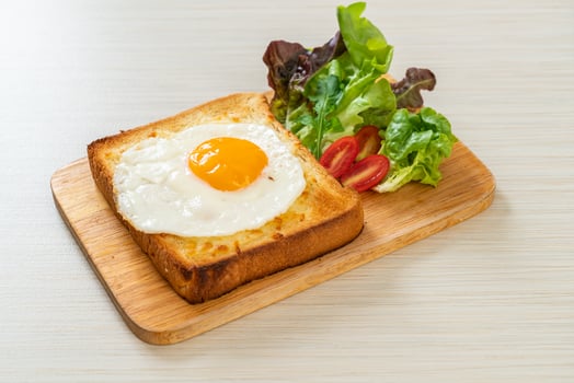 Homemade bread toasted with cheese and fried egg on top with vegetable salad for breakfast photo