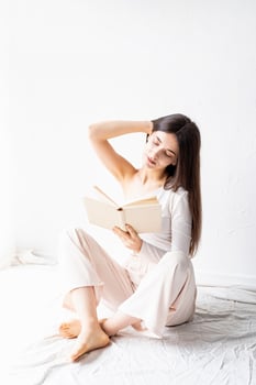 Woman in white cozy clothes reading a book photo