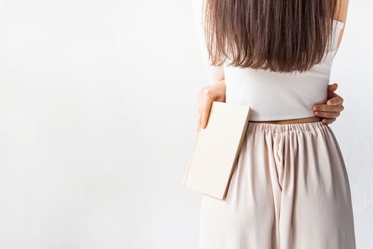 woman on white background holding a book, view from behind photo