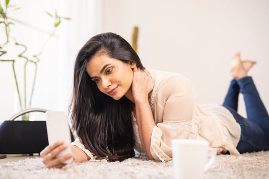 Attractive young Indian woman relaxing with mobile at home. photo
