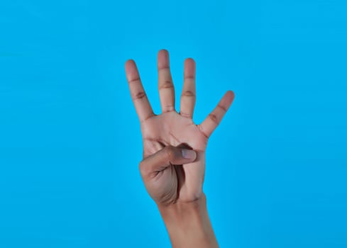 closeup hand showing number four 4 with hand. blue background. photo