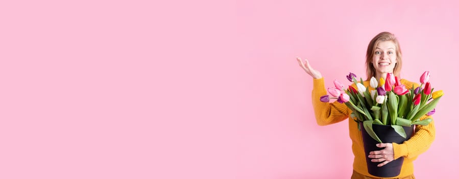 woman holding a bucket of fresh tulips isolated on pink photo