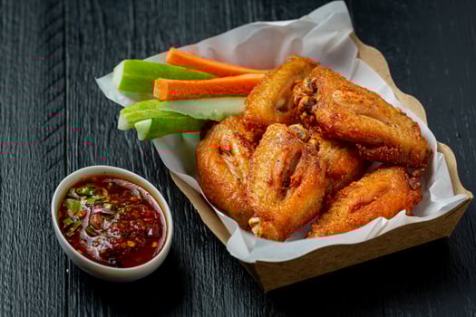 Chicken wings in paper box on a black photo