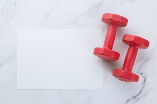 Blank white paper note and fitness equipment on marble background photo