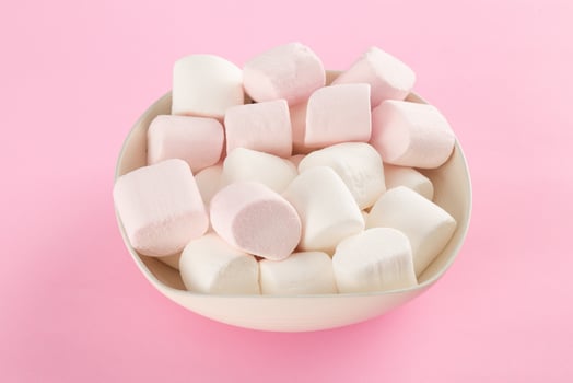 Marshmallow in bowl on pastel pink background photo