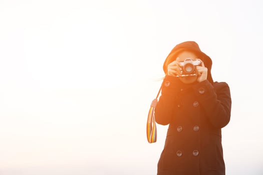 Young woman wearing black coat standing carry retro camera photo