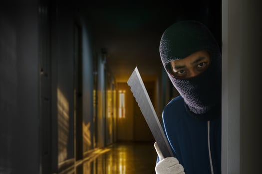 Masked robber with knife hiding behind the door photo