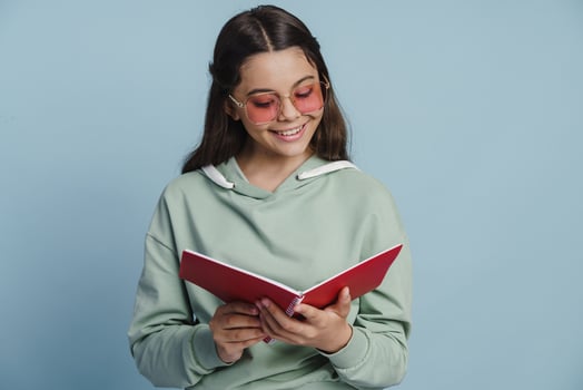 Positive, smiling girl writes something in a notebook photo