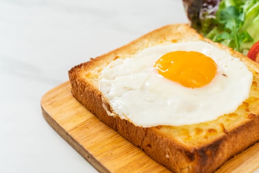 Homemade bread toasted with cheese and fried egg on top with vegetable salad for breakfast photo