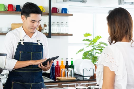 young barista taking order of coffee from customer in cafe photo