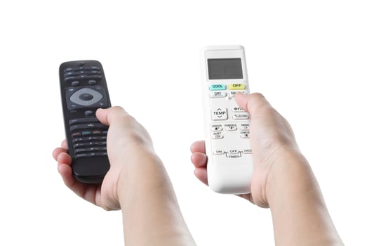 Hand holding air conditioner and television remote control photo
