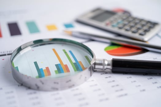 Magnifying glass on charts graphs paper. photo