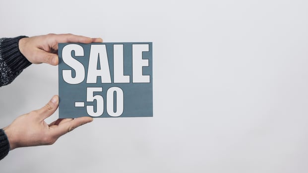 Close Up Of Man Hands Holding A Sign Saying Sale -50 photo