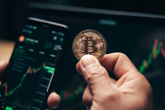 Businessman holding golden bitcoin on computer trading chart screen photo
