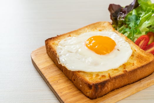 Homemade bread toasted with cheese and fried egg on top with vegetable salad for breakfast photo