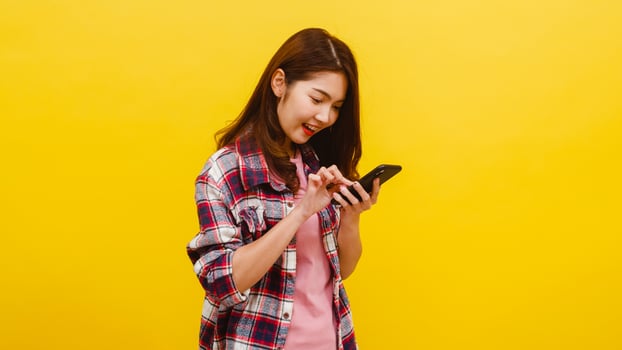 Asian female using phone with positive expression, smiles broadly. photo