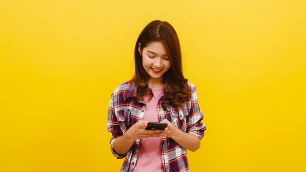 Asian female using phone with positive expression, smiles broadly. photo