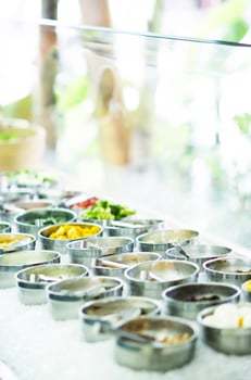 Bowls of mixed fresh organic red peppers and vegetables in modern salad bar display photo