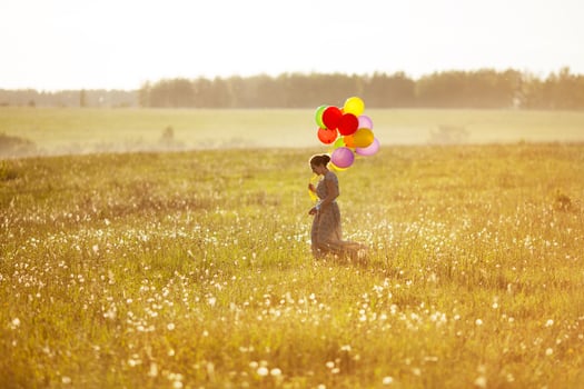 Young happy woman with balloons in a field photo