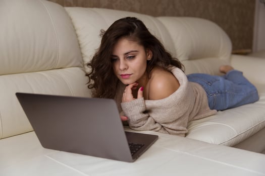 Woman is lying on the sofa with laptop photo