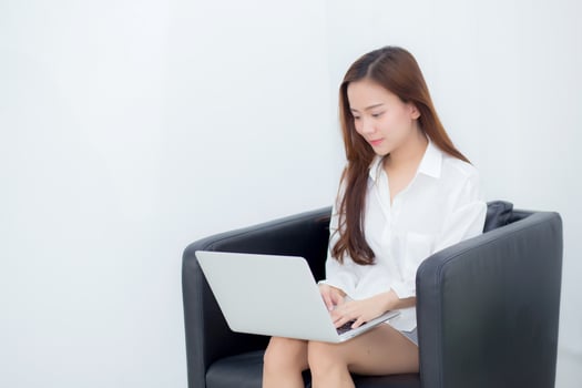 Young asian woman using laptop for leisure on sofa. photo
